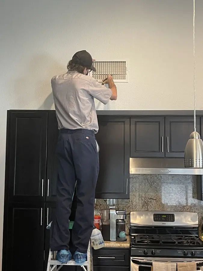 Technician inspecting an air vent during HVAC service in Oxon Hill